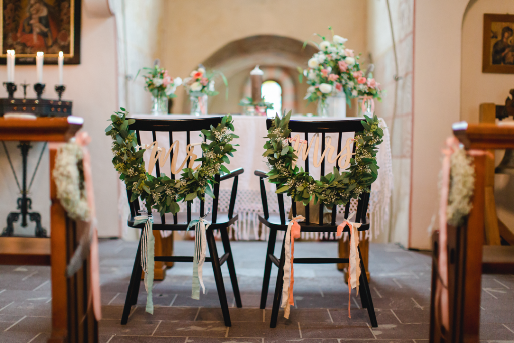 zwei mit Blumenschmuck dekorierte Stühle in einer Kirche
