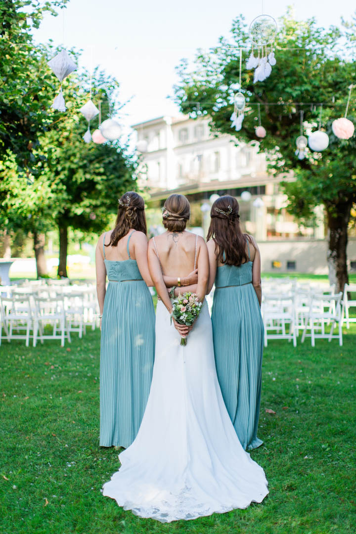 Braut in weissem Brautkleid mit ihren zwei Trauzeuginnen in türkisem Kleid zu ihrer Seite