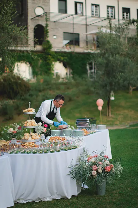 ein Kellner richtet Essen auf einem festlich dekorierten Buffetisch an